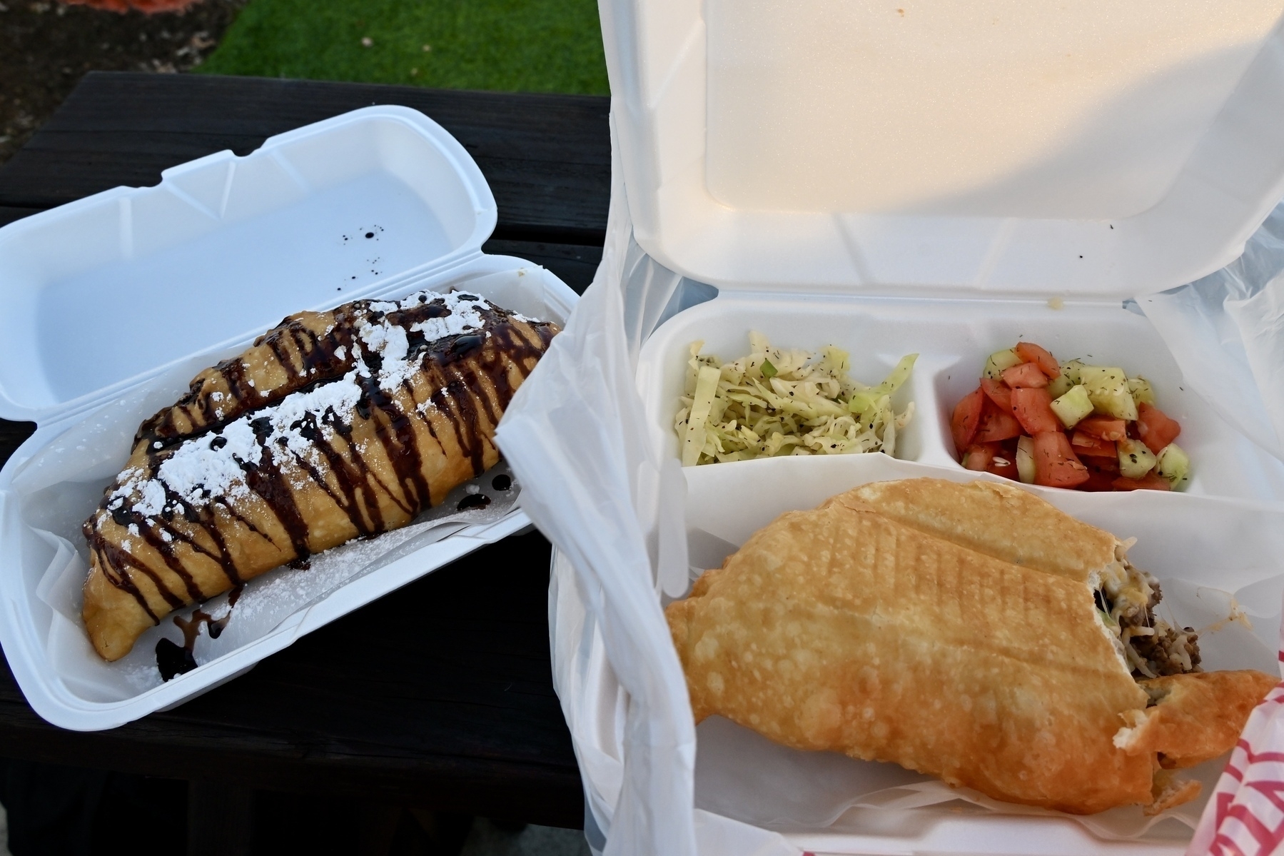 A meal includes a dessert topped with chocolate sauce and powdered sugar on the left, and a savory pastry accompanied by shredded cabbage and tomato-cucumber salad on the right.