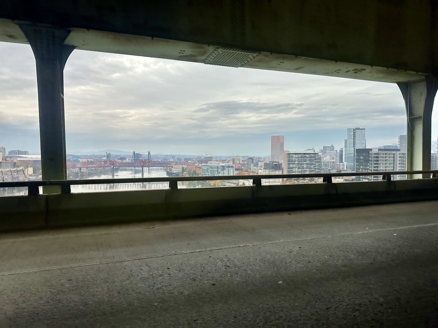 A view of a cityscape seen from a highway, featuring tall buildings and a cloudy sky.