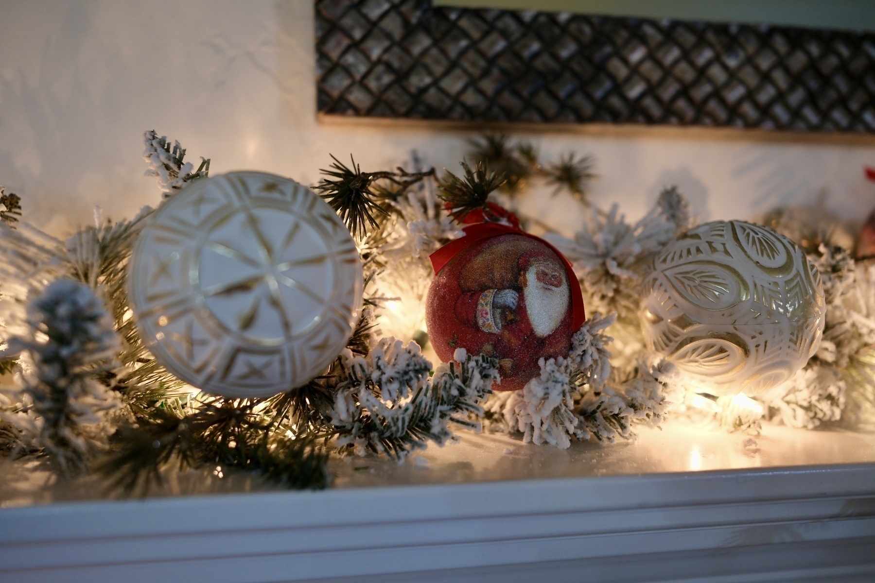 A festive arrangement of Christmas ornaments and decorative greenery is lit with soft white lights.