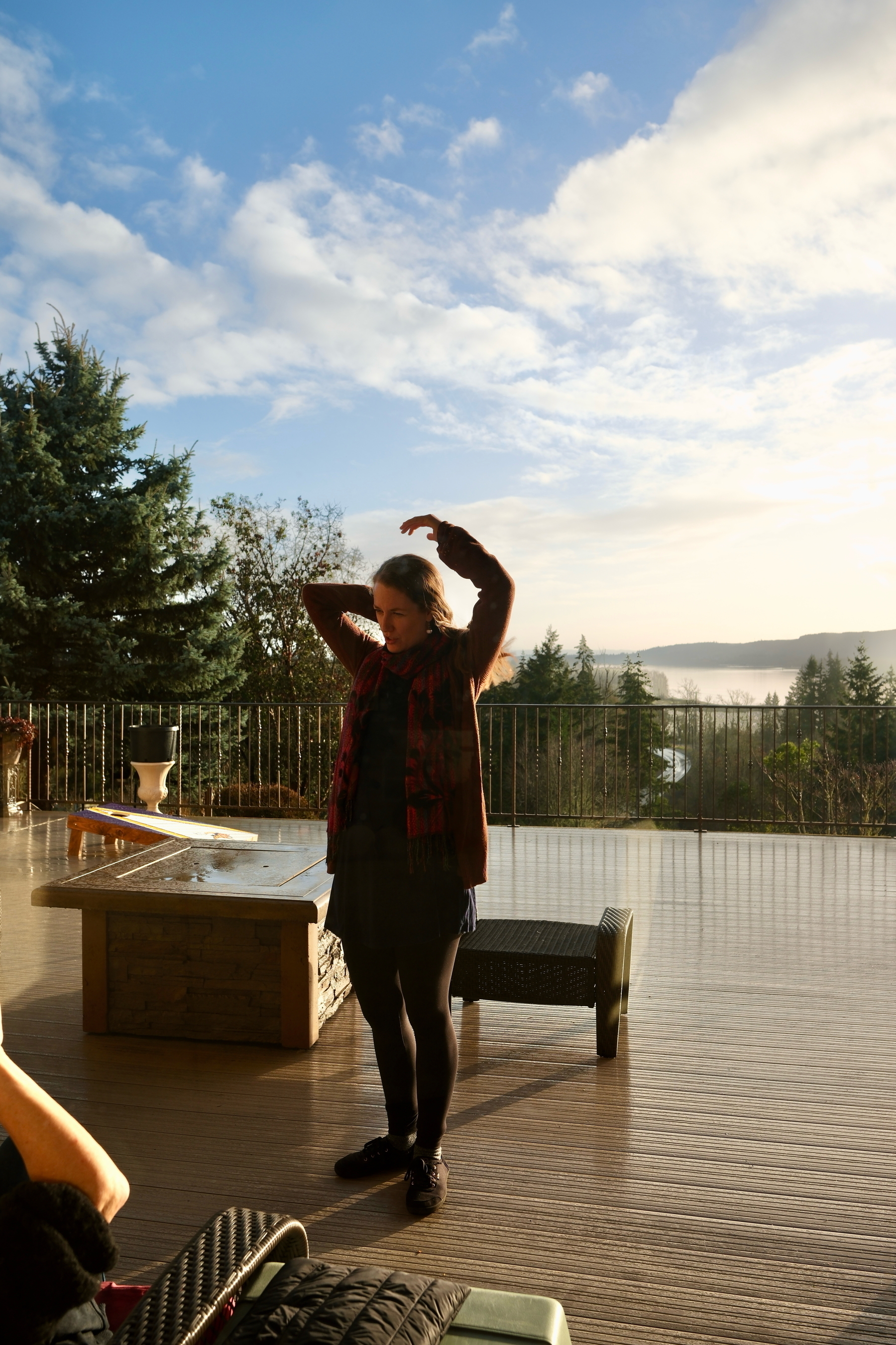 My wife, a blond middle aged woman on a deck after a rain, some blue in the sky, and the Colombia River off in the distance. 